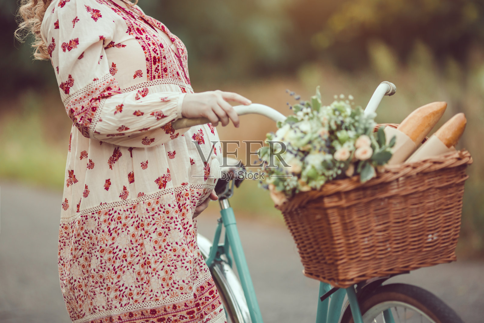 孕妇肚皮迎大自然特写。女人复古的法国风格与自行车在森林道路上照片摄影图片