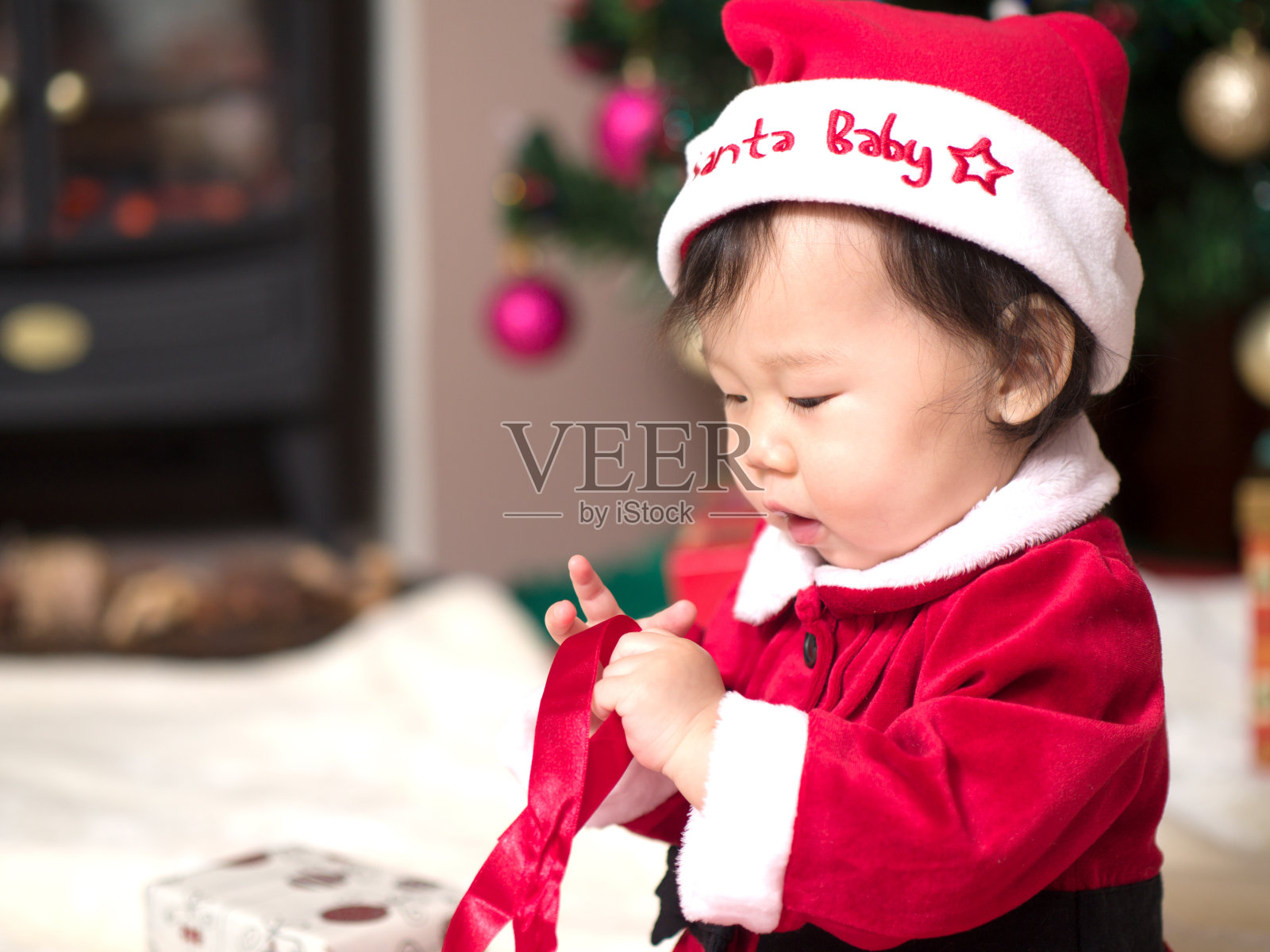 亚洲女婴在圣诞老人服装打开礼盒照片摄影图片