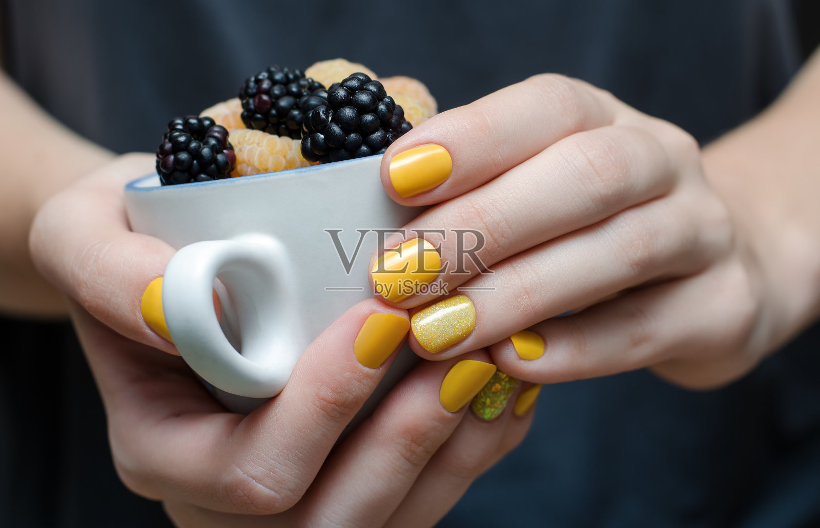 女性的手与黄色指甲设计。照片摄影图片