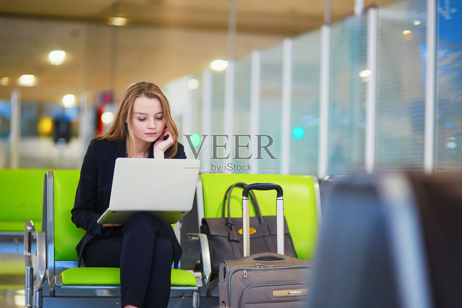 一个在国际机场候机楼里用笔记本电脑工作的女人照片摄影图片