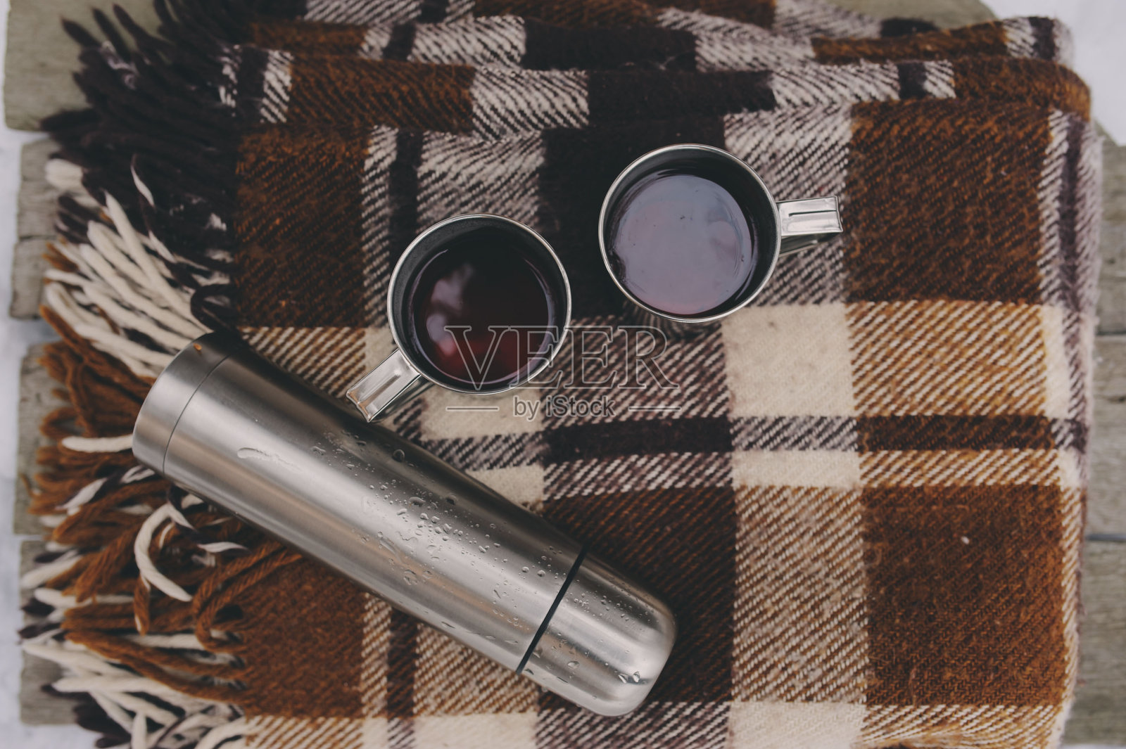冬天在雪地上野餐。热茶，热水瓶放在毯子上。照片摄影图片