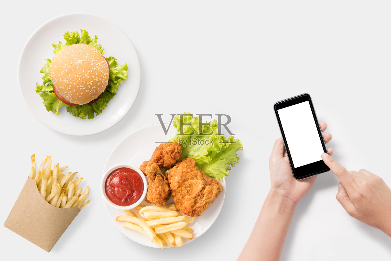 模拟使用智能手机与汉堡，炸薯条，炸鸡套餐。照片摄影图片