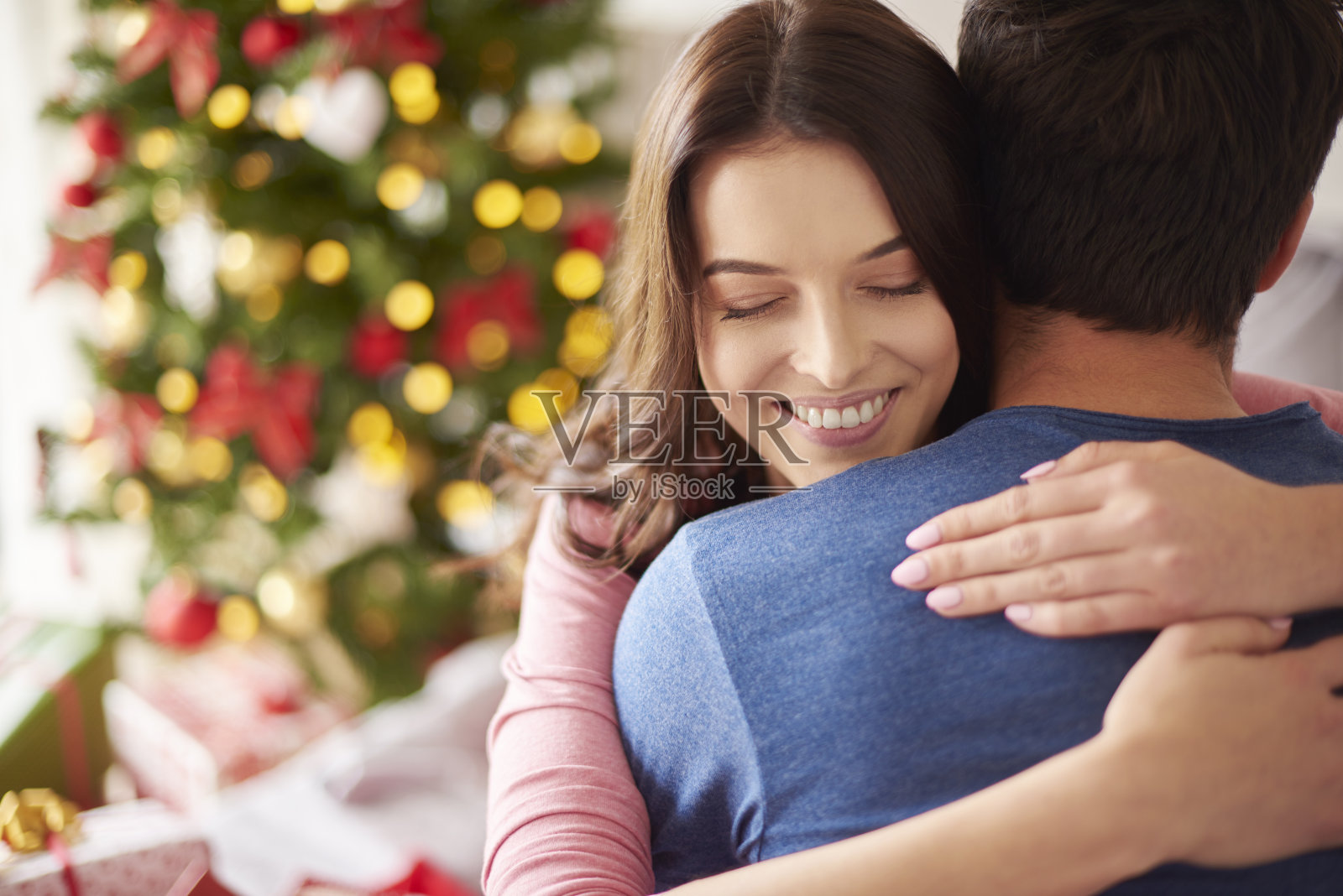 微笑的女人拥抱她的男朋友在圣诞节照片摄影图片