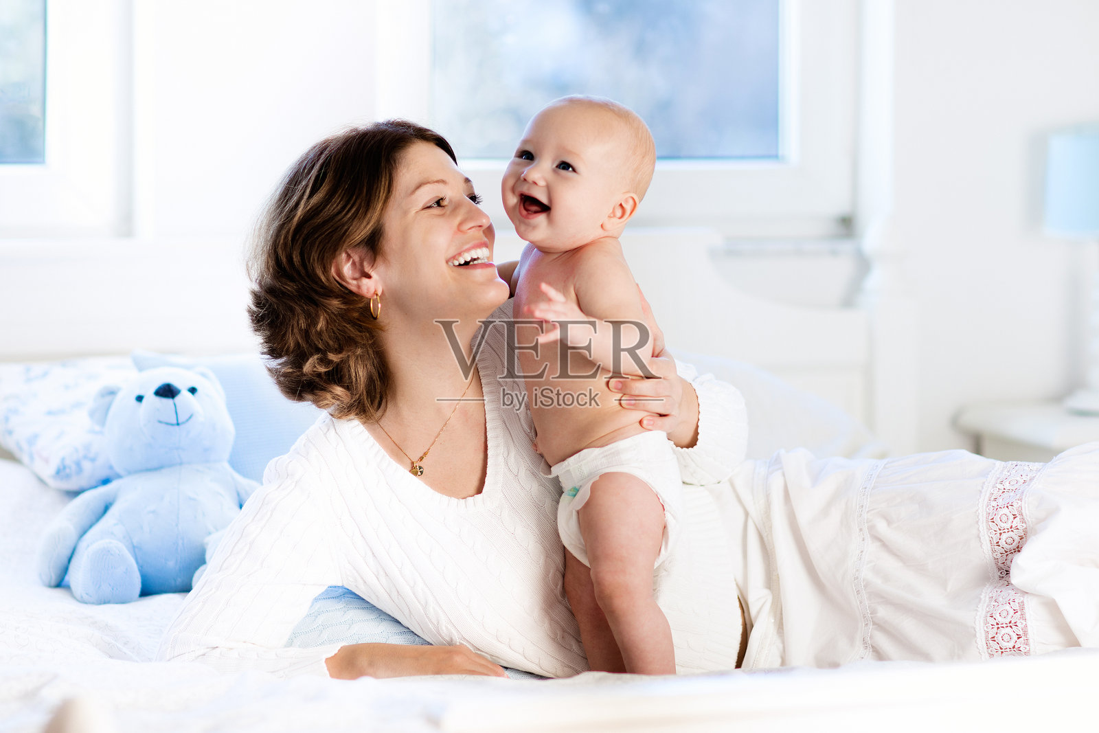 婴儿和妈妈在家里的床上。妈妈和孩子。照片摄影图片