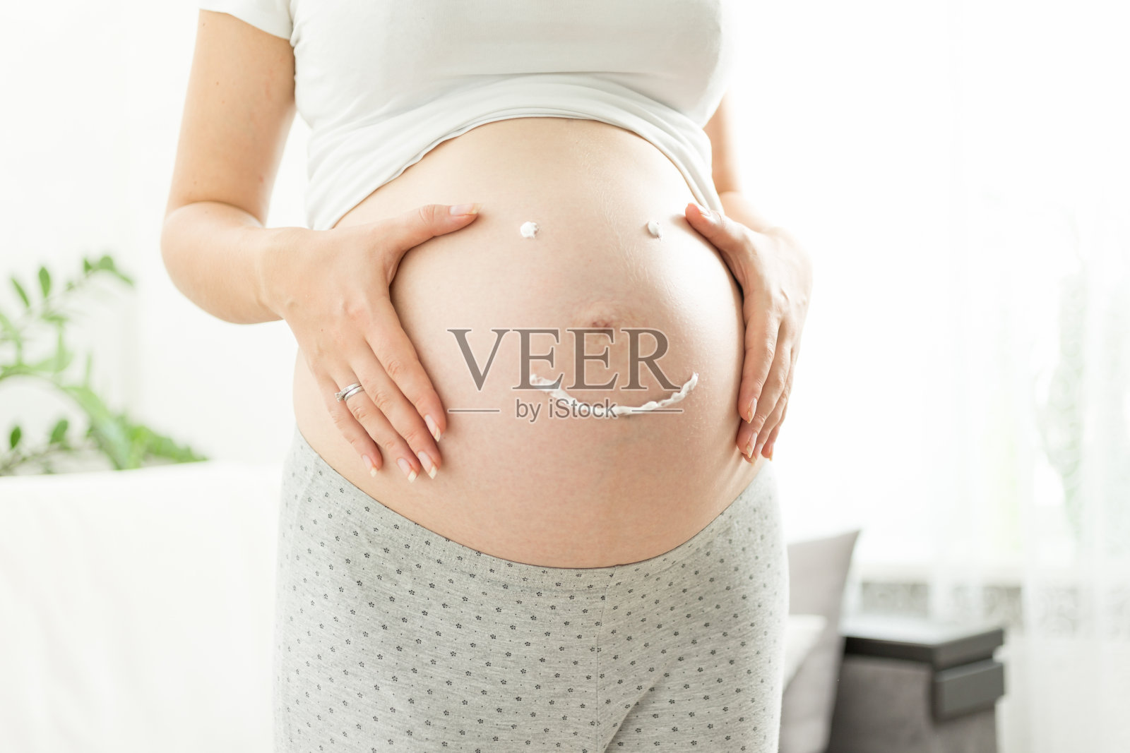 微笑的孕妇用乳膏画妊娠纹照片摄影图片