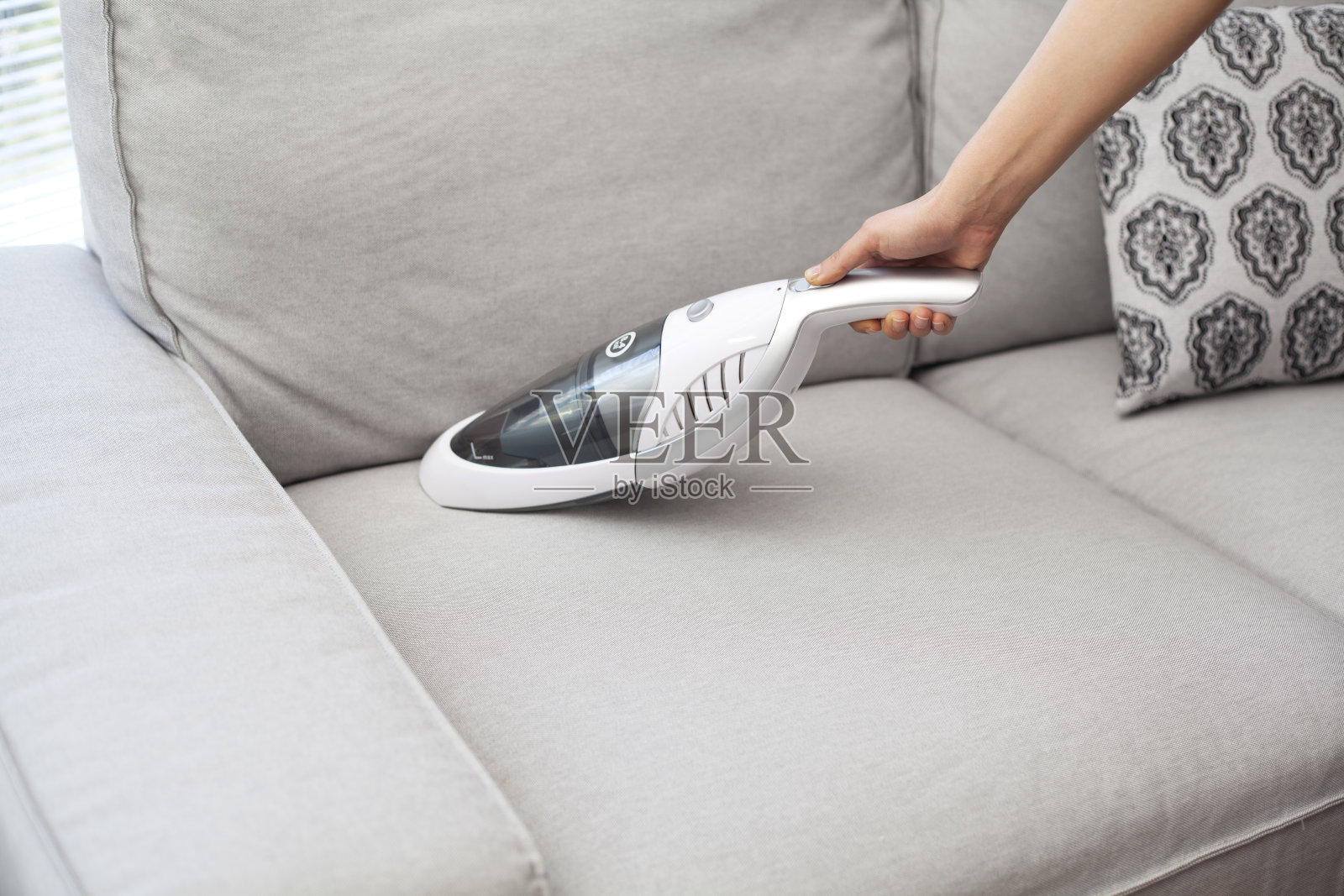 用手持式吸尘器清洁沙发的女人照片摄影图片