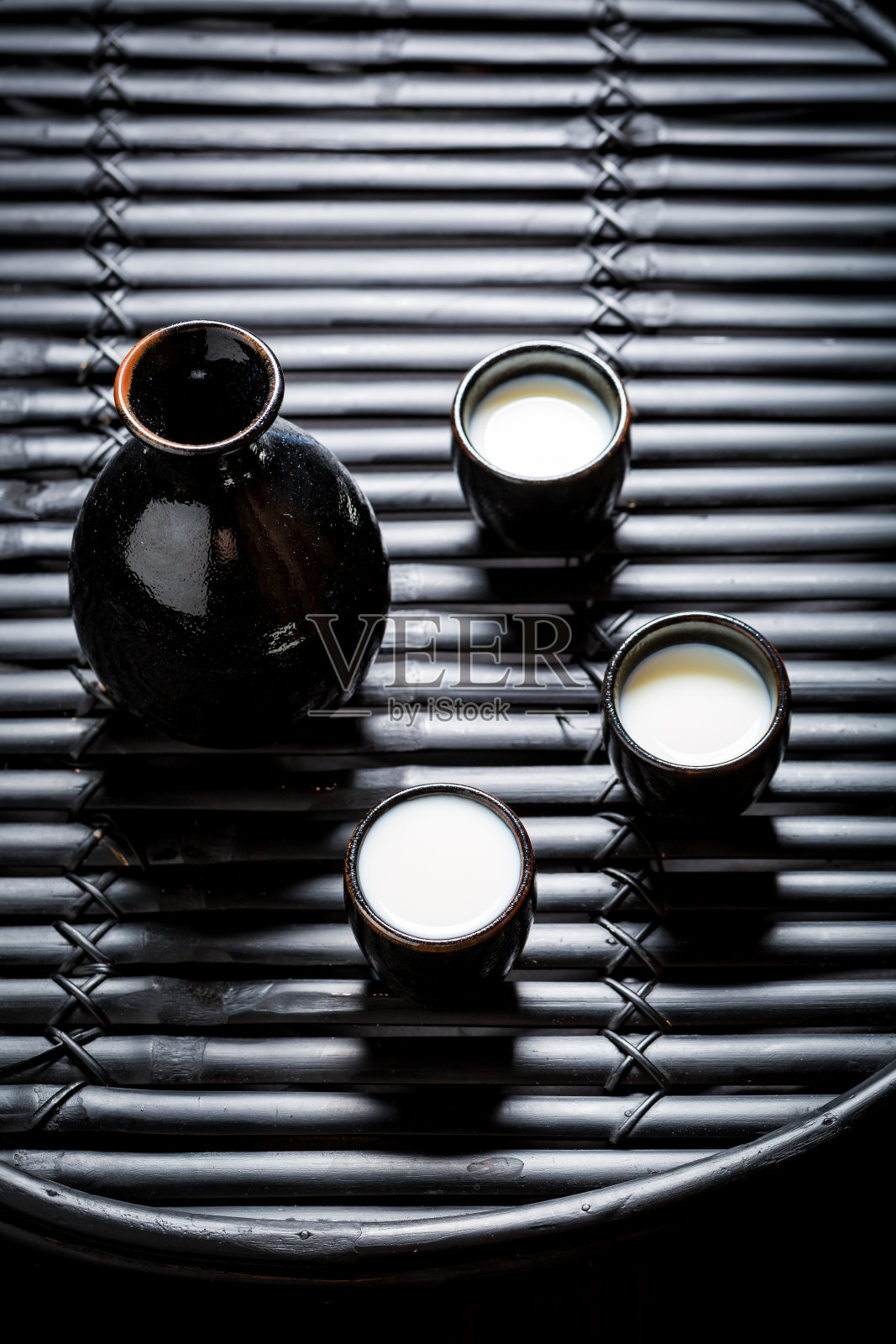 准备饮用的清酒在黑色的陶瓷在黑色的桌子照片摄影图片