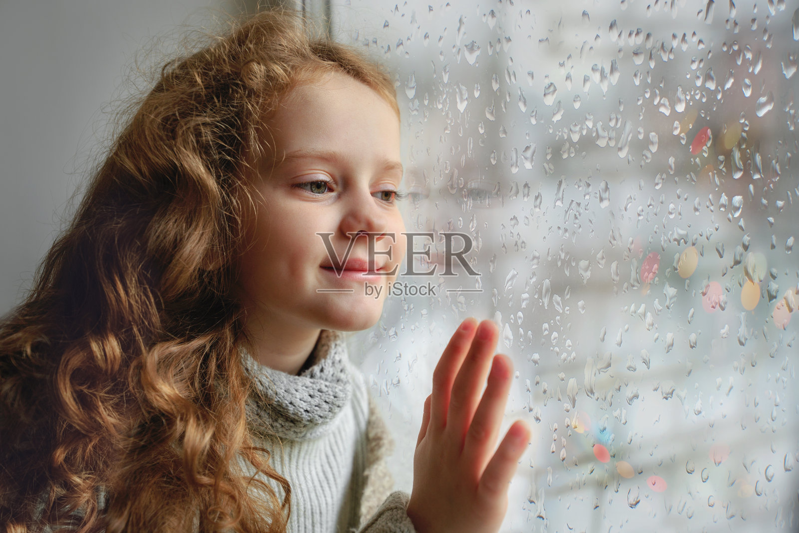 可爱的小女孩坐在窗边。照片摄影图片