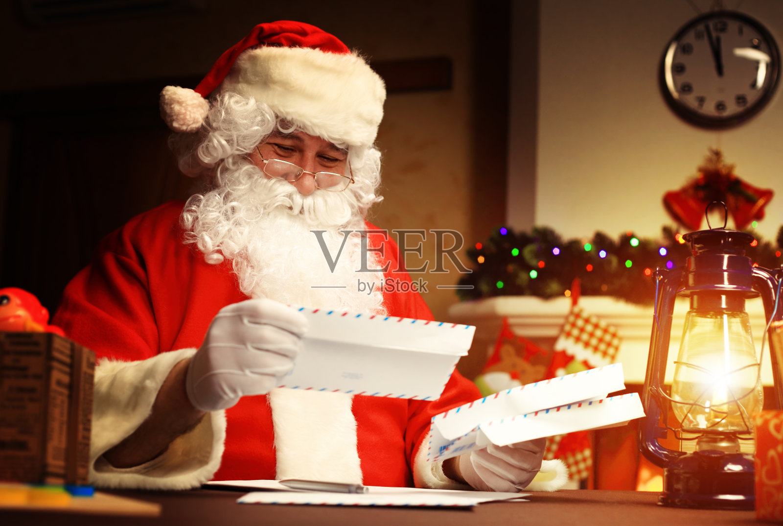 圣诞老人坐在圣诞树旁，读着圣诞信照片摄影图片
