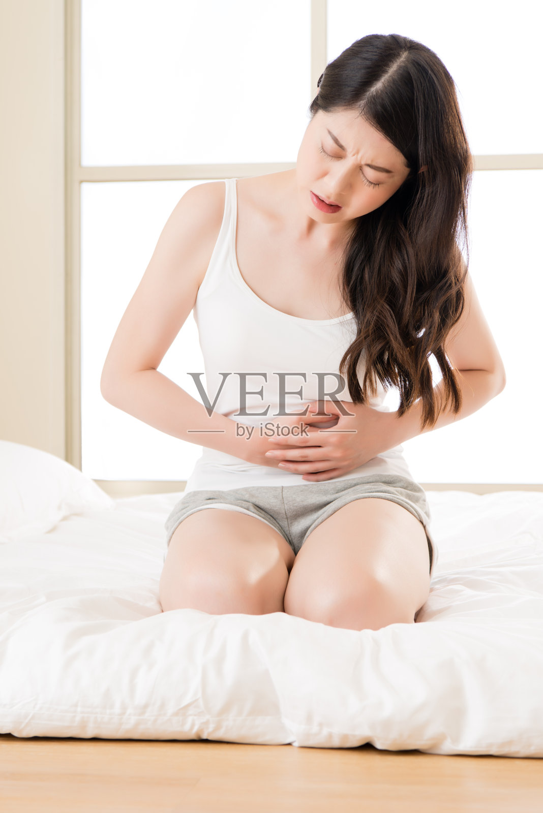 美丽的亚洲女人在床上遭受胃痛照片摄影图片