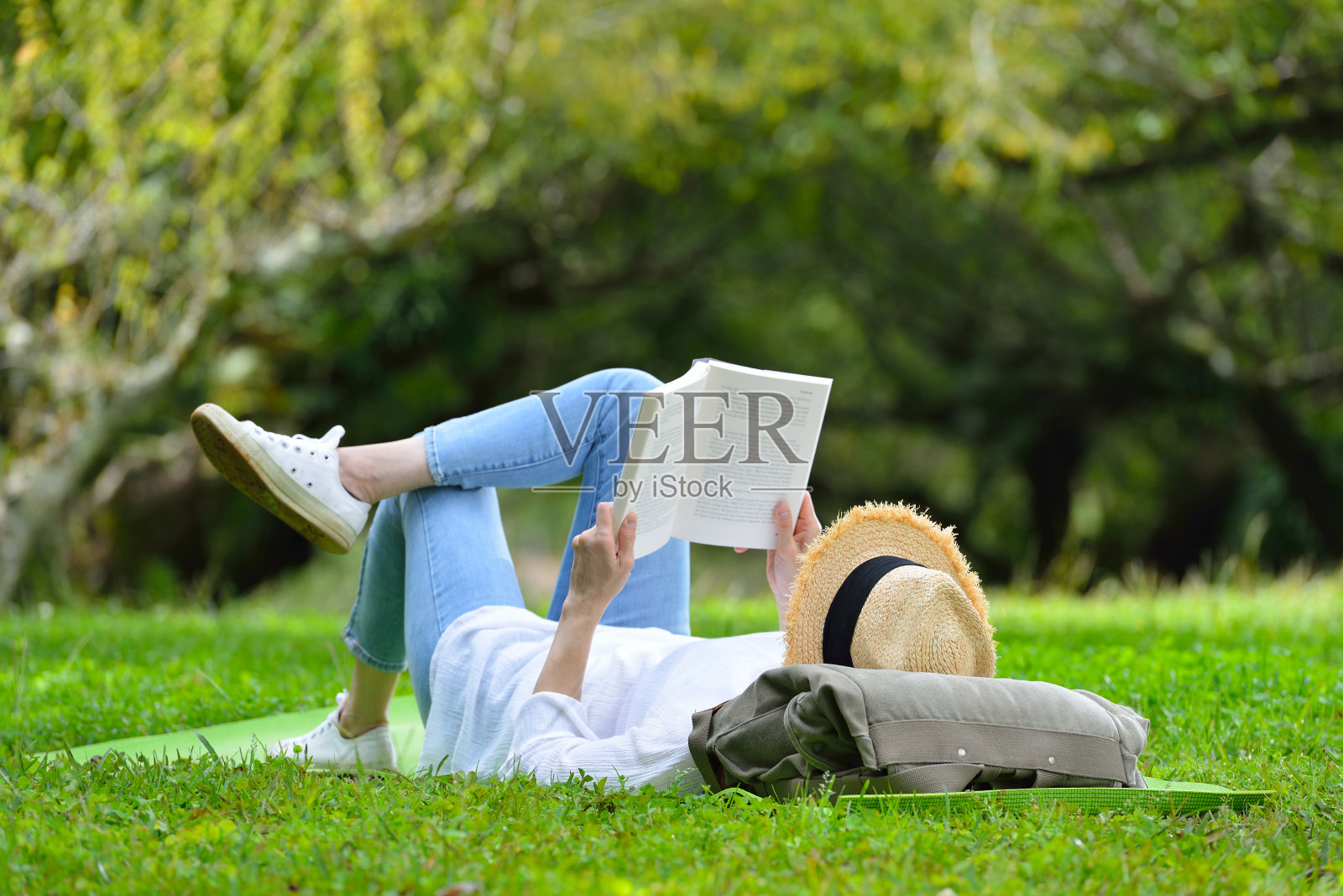 女人躺在绿色的草地上看书照片摄影图片