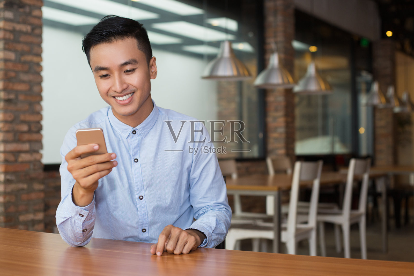 微笑的亚洲男人在咖啡桌上使用智能手机照片摄影图片