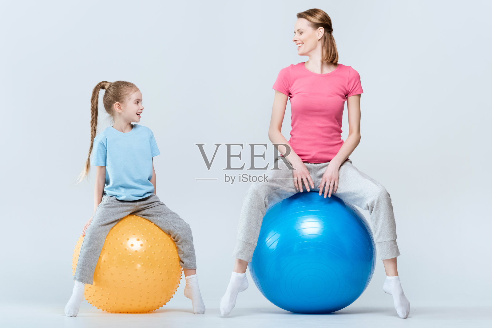 母亲和女儿在白色的健身球上锻炼照片摄影图片
