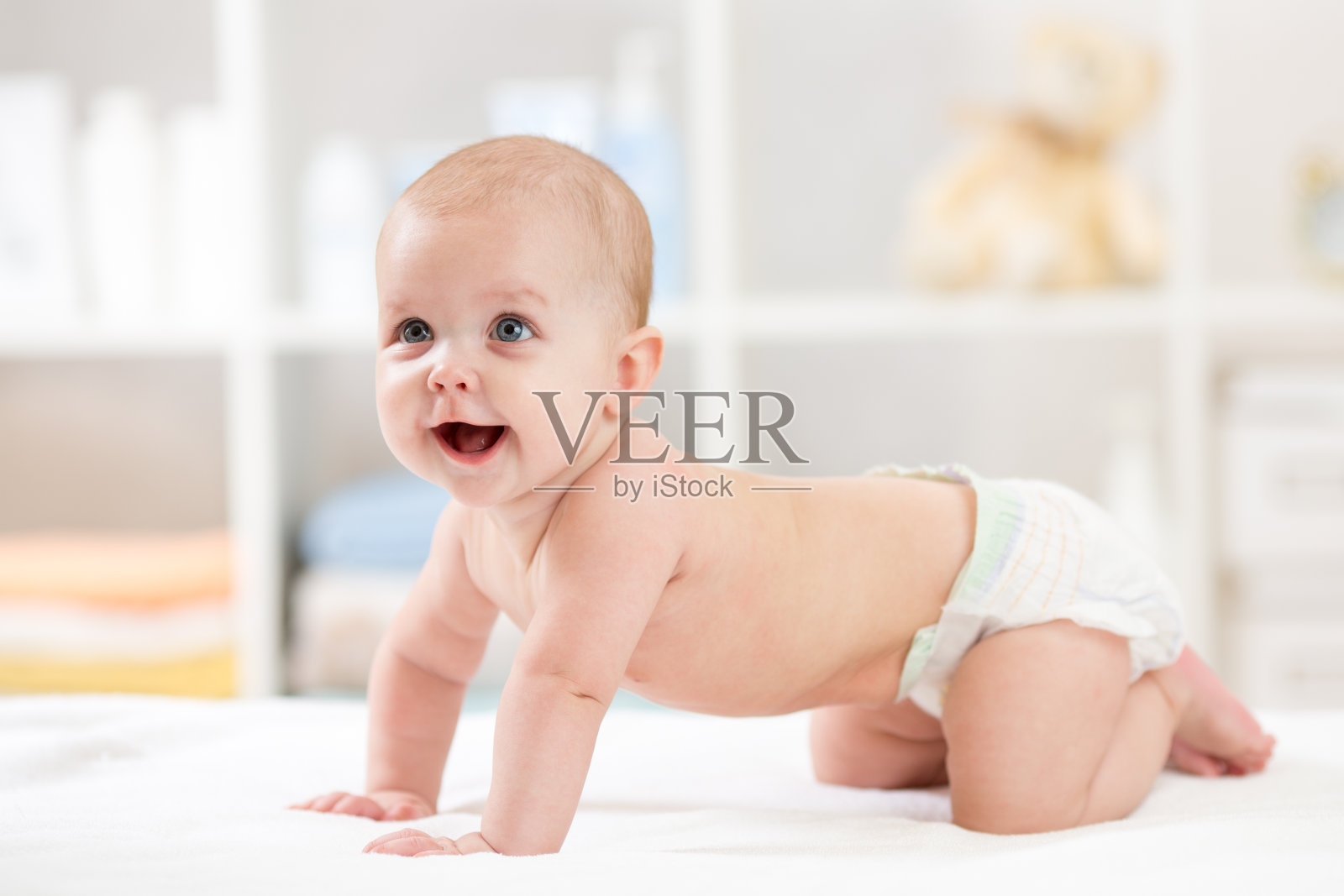 可爱的婴儿爬在白色的毯子上照片摄影图片