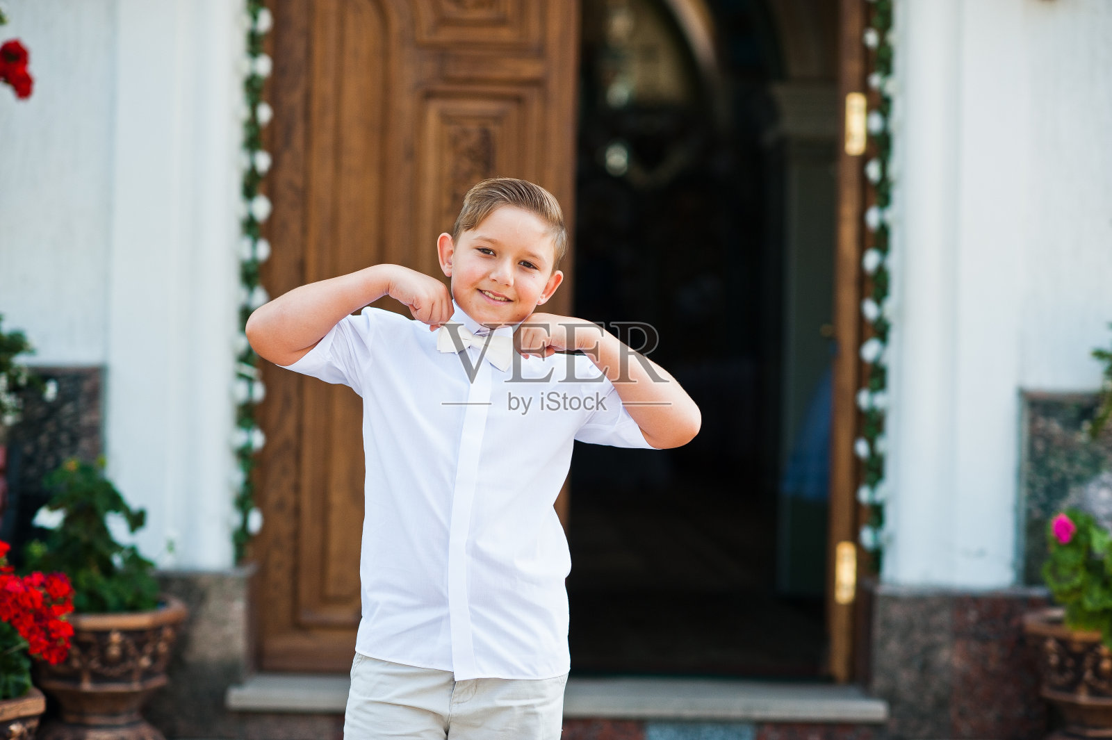 小男孩的肖像在白色的戴和领结在第一圣餐背景教堂的大门照片摄影图片