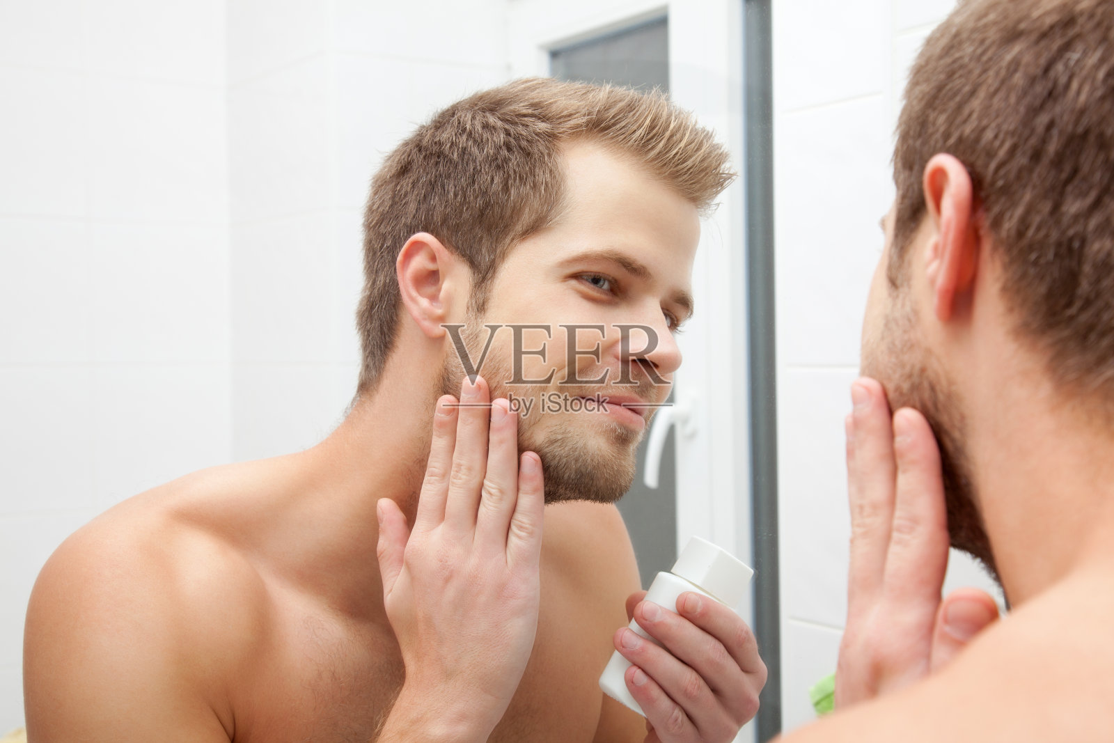 微笑的男人在脸上涂抹洁面乳照片摄影图片