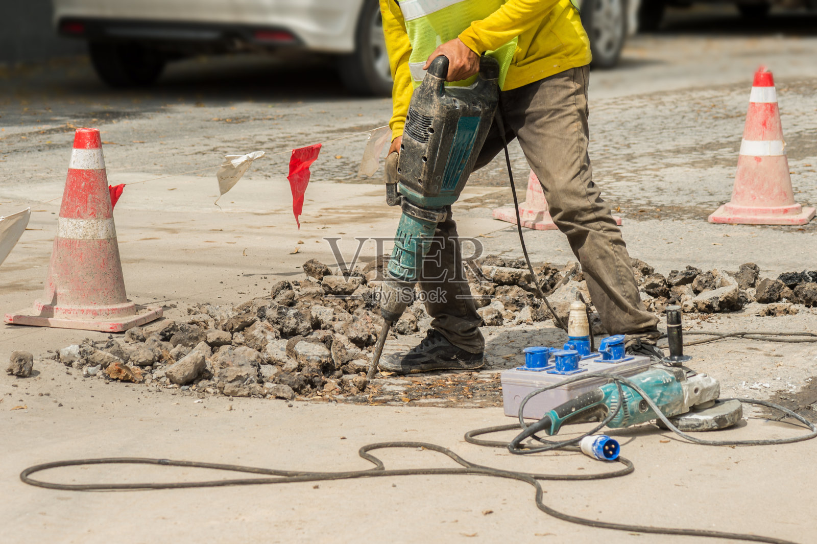 工人用手提钻钻混凝土车道。照片摄影图片