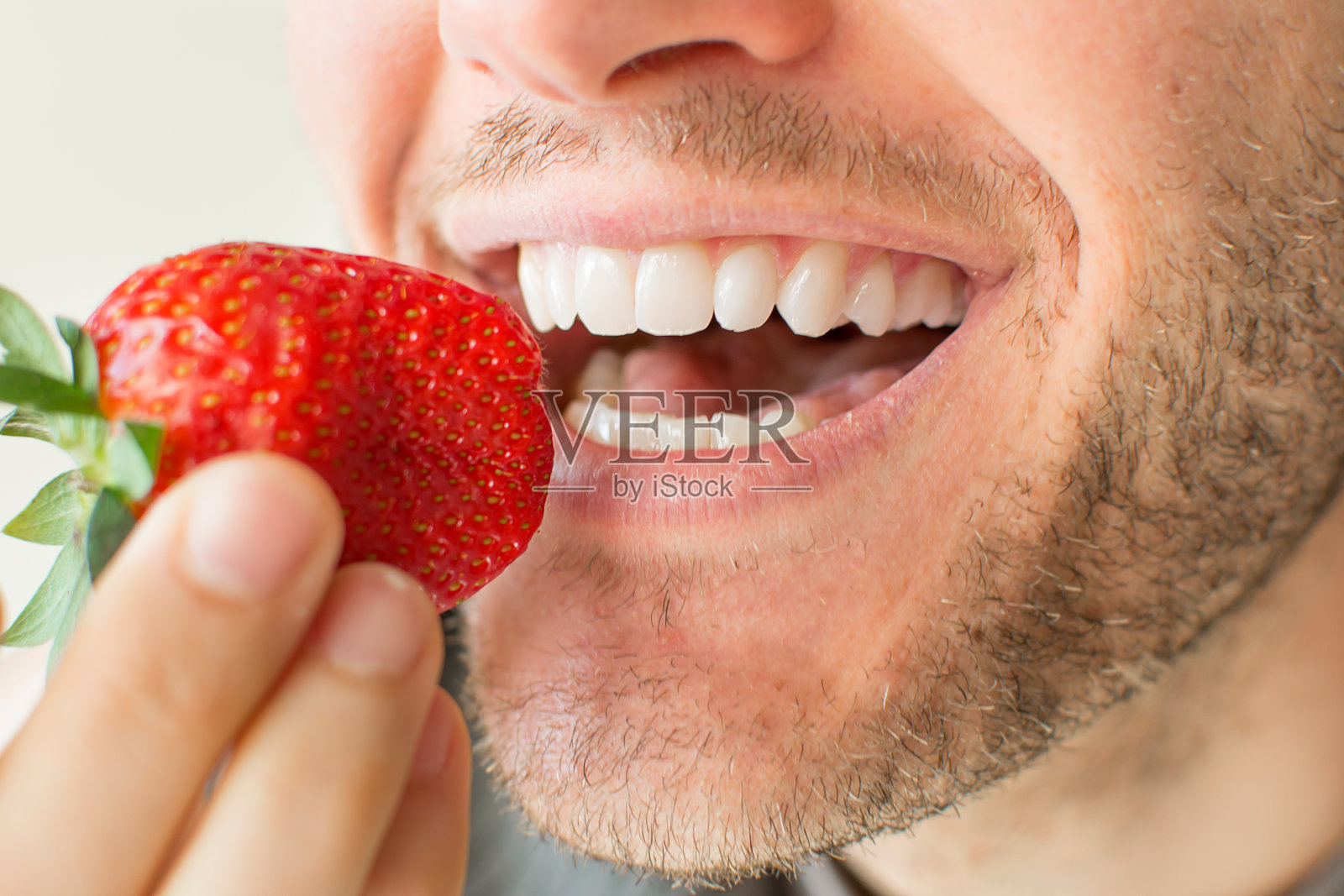 一个男人吃草莓的特写照片摄影图片
