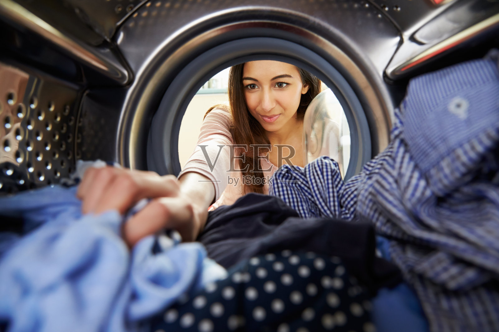洗衣服的女人把手伸进洗衣机里照片摄影图片