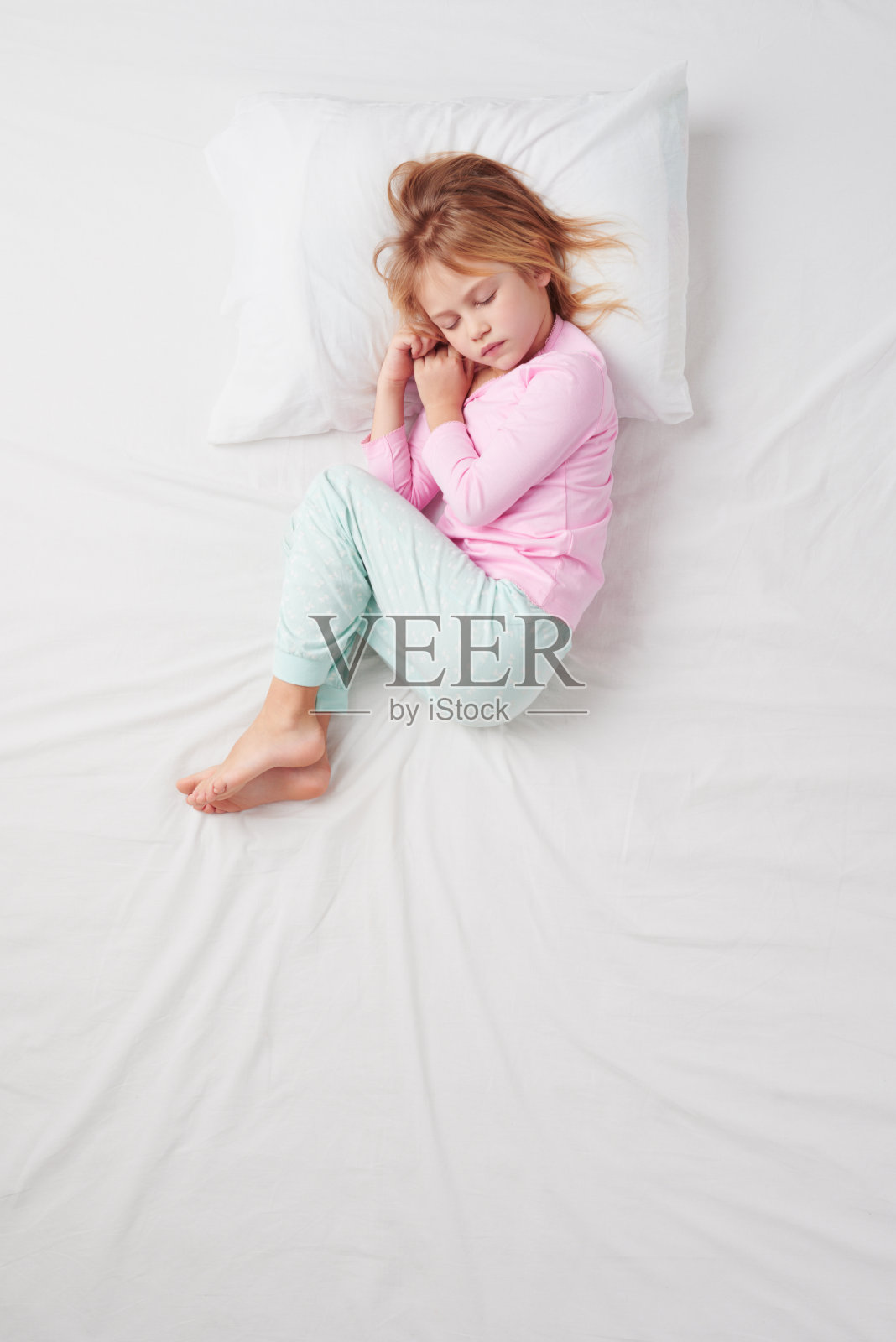 俯视图小女孩睡在胎儿的姿势照片摄影图片