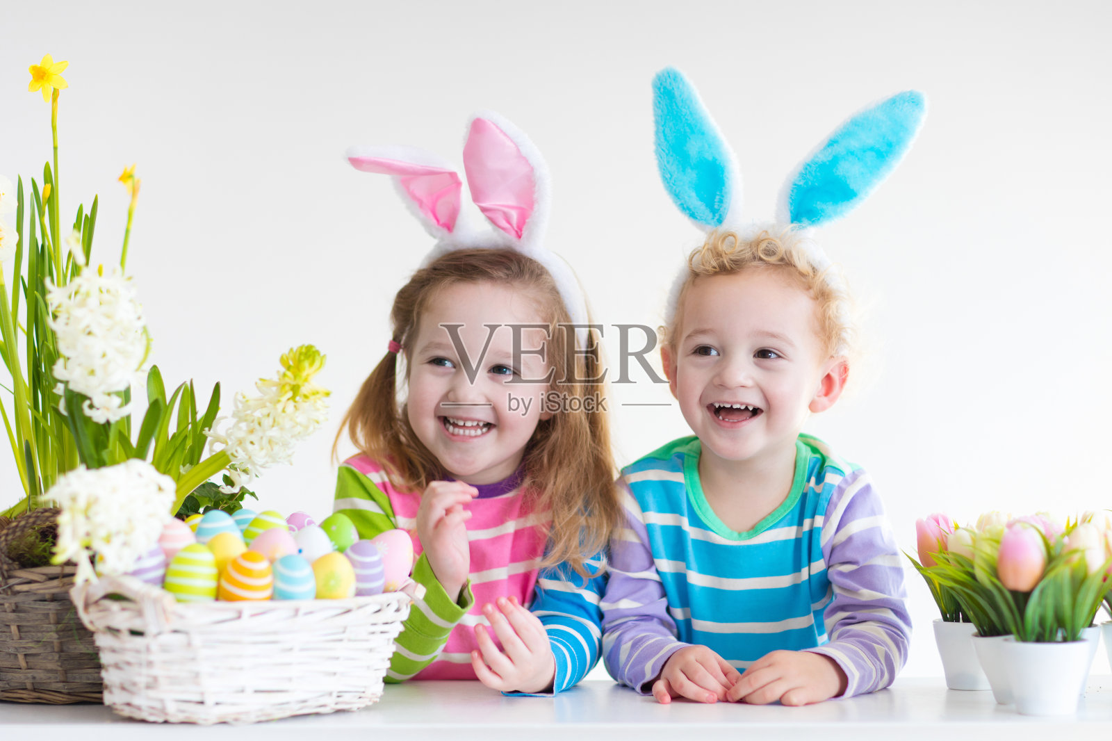 在寻找复活节彩蛋时，挂着兔子耳朵的孩子们笑着照片摄影图片
