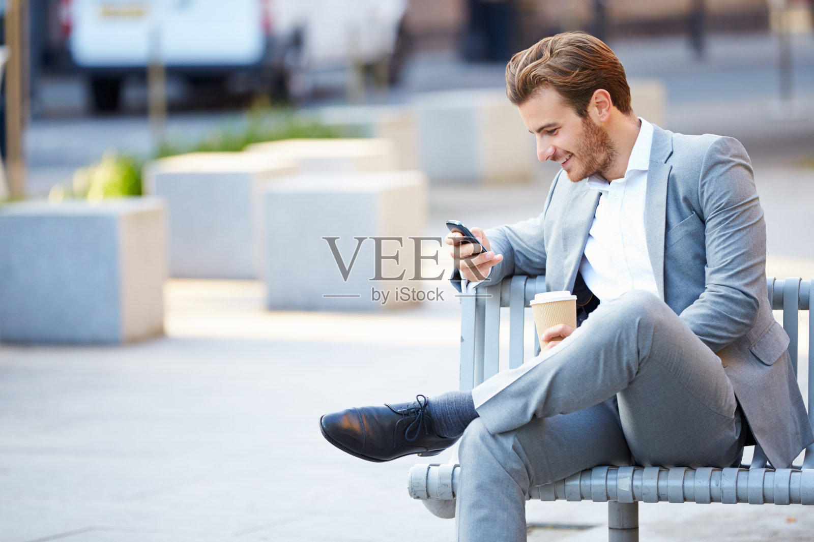 商人在公园长椅上用手机喝咖啡照片摄影图片