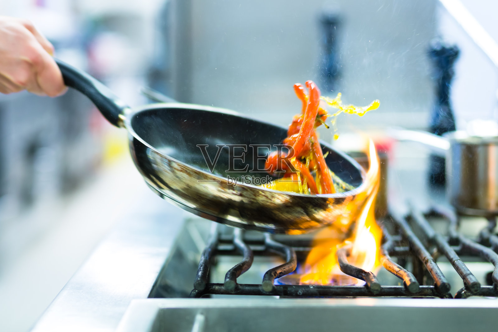 厨师在餐厅厨房的炉子上用平底锅照片摄影图片