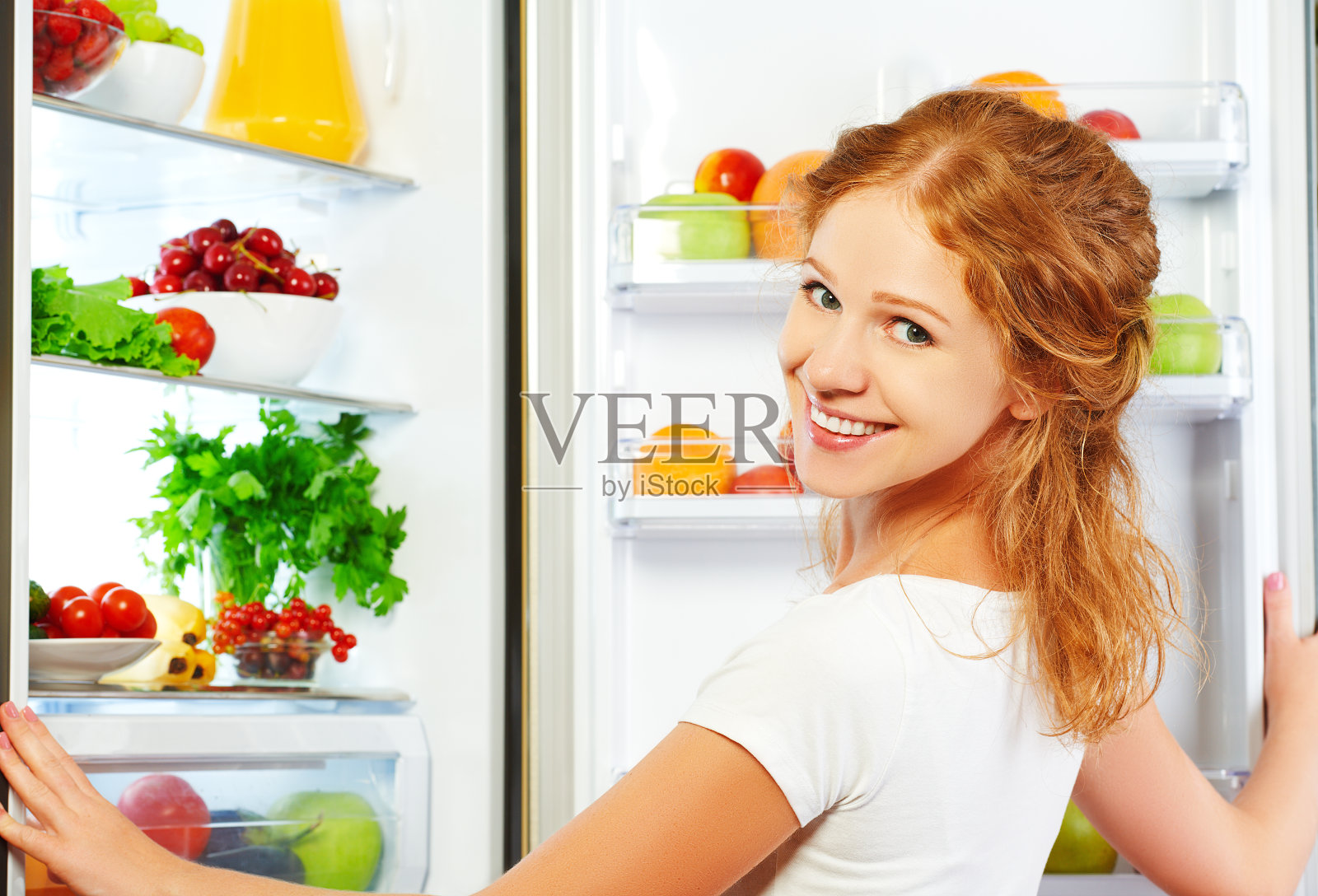 幸福的女人和他开冰箱吃水果、蔬菜照片摄影图片