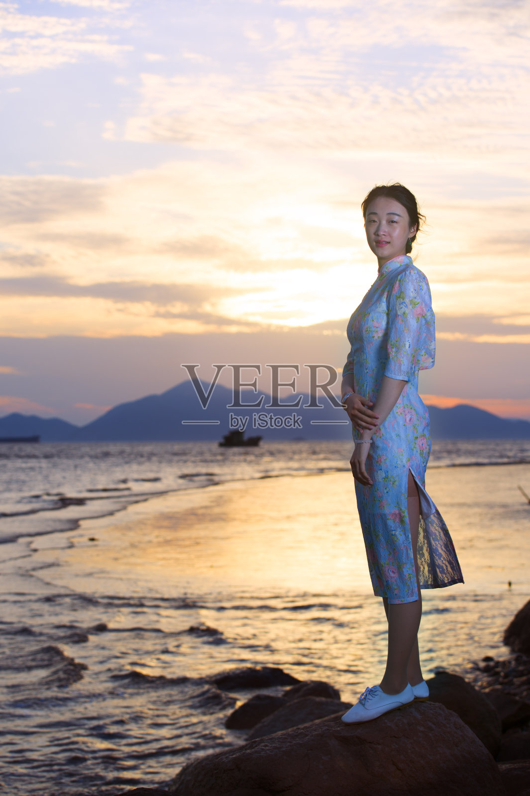 穿着旗袍的女人站在沙滩上照片摄影图片