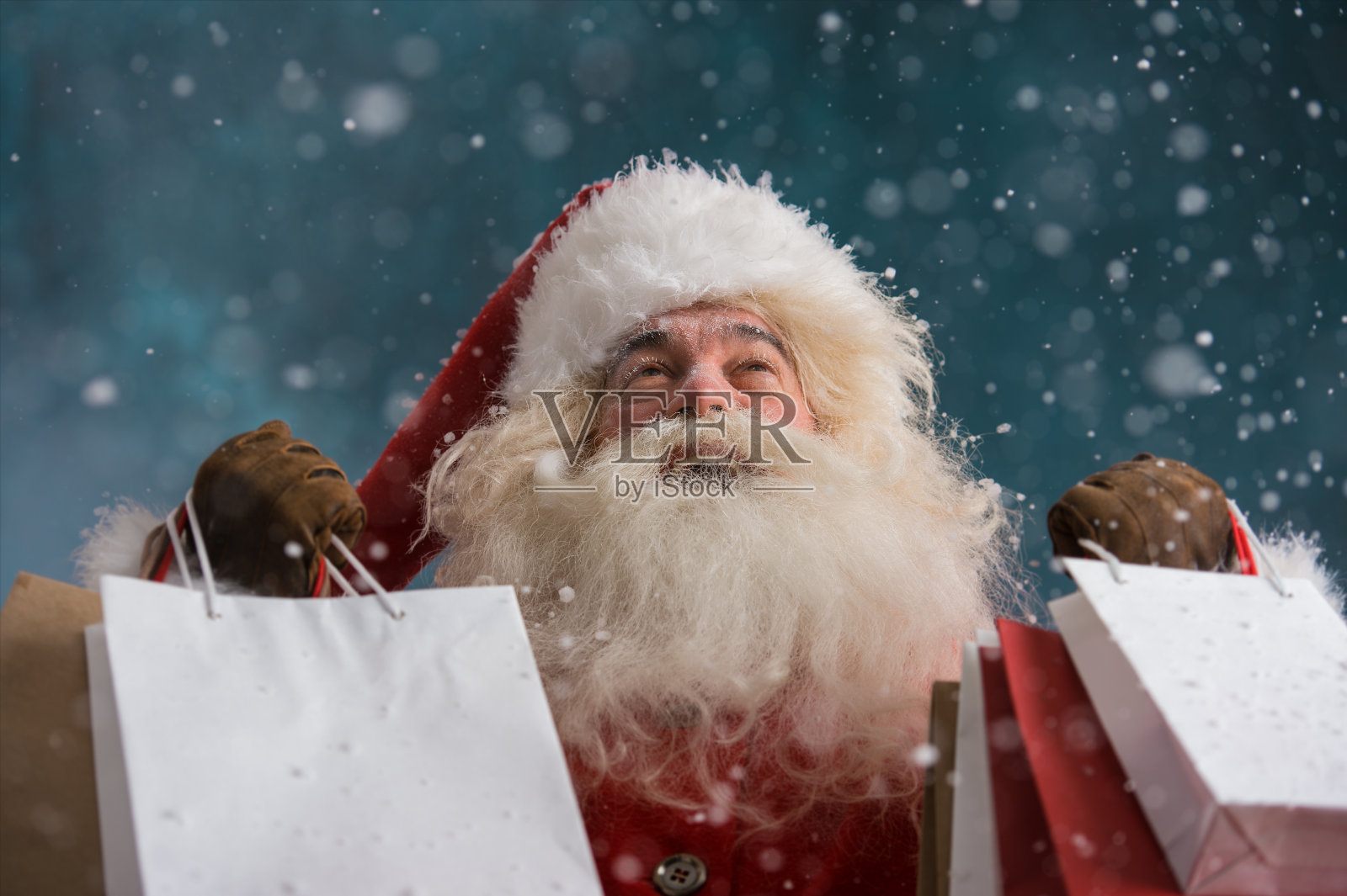 圣诞老人在下雪的户外拿着购物袋照片摄影图片