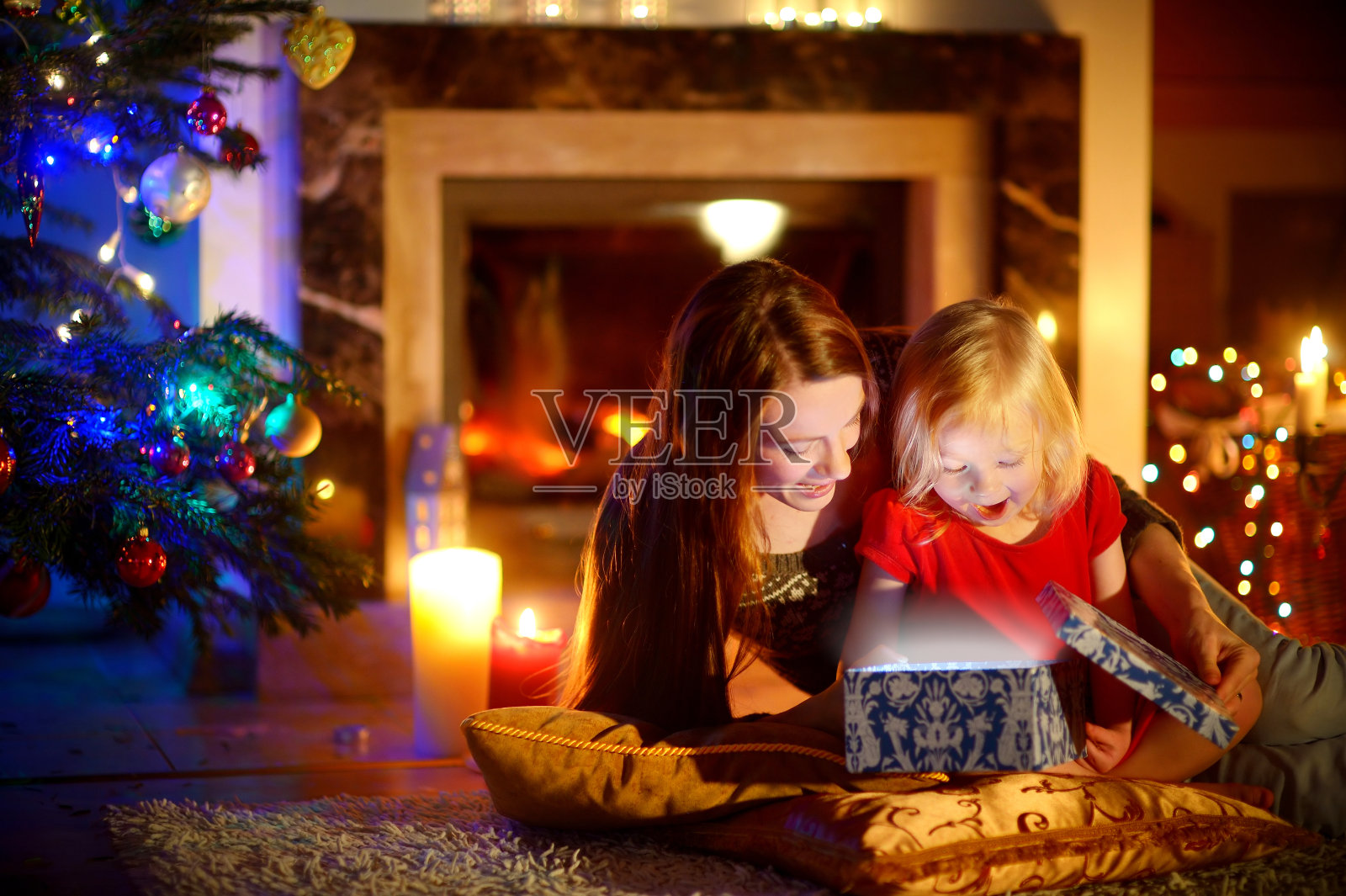 妈妈和小女儿打开一份神奇的圣诞礼物照片摄影图片