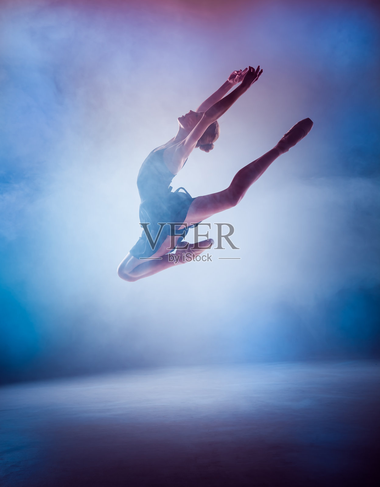 年轻芭蕾舞者在蓝色上跳跃的剪影照片摄影图片