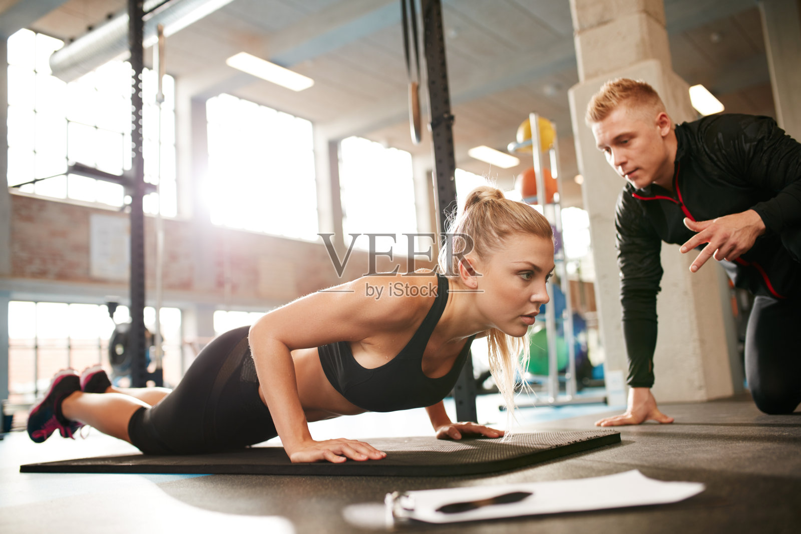 女性在健身房与私人教练锻炼照片摄影图片