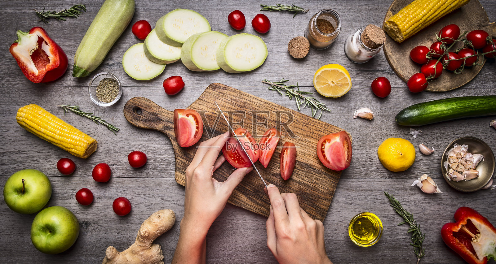 女性手切西红柿质朴的厨房餐桌，素食的概念。照片摄影图片