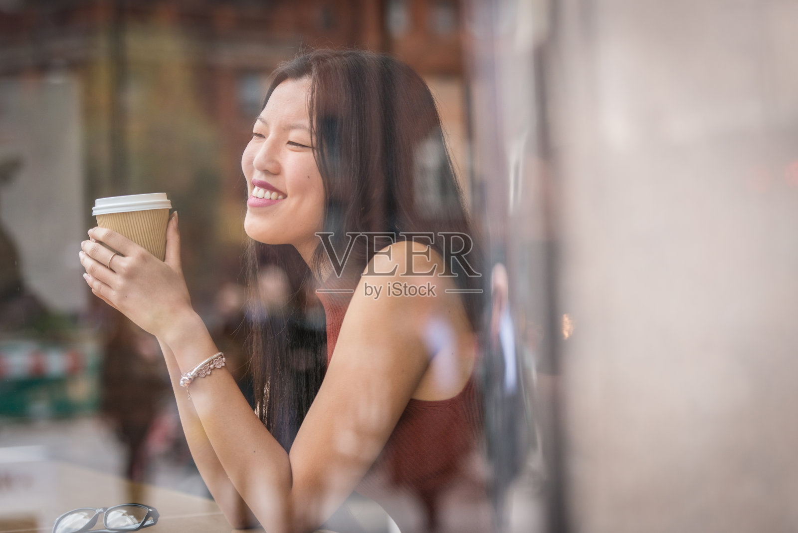 年轻的中国女人坐在窗户旁边的咖啡馆。照片摄影图片