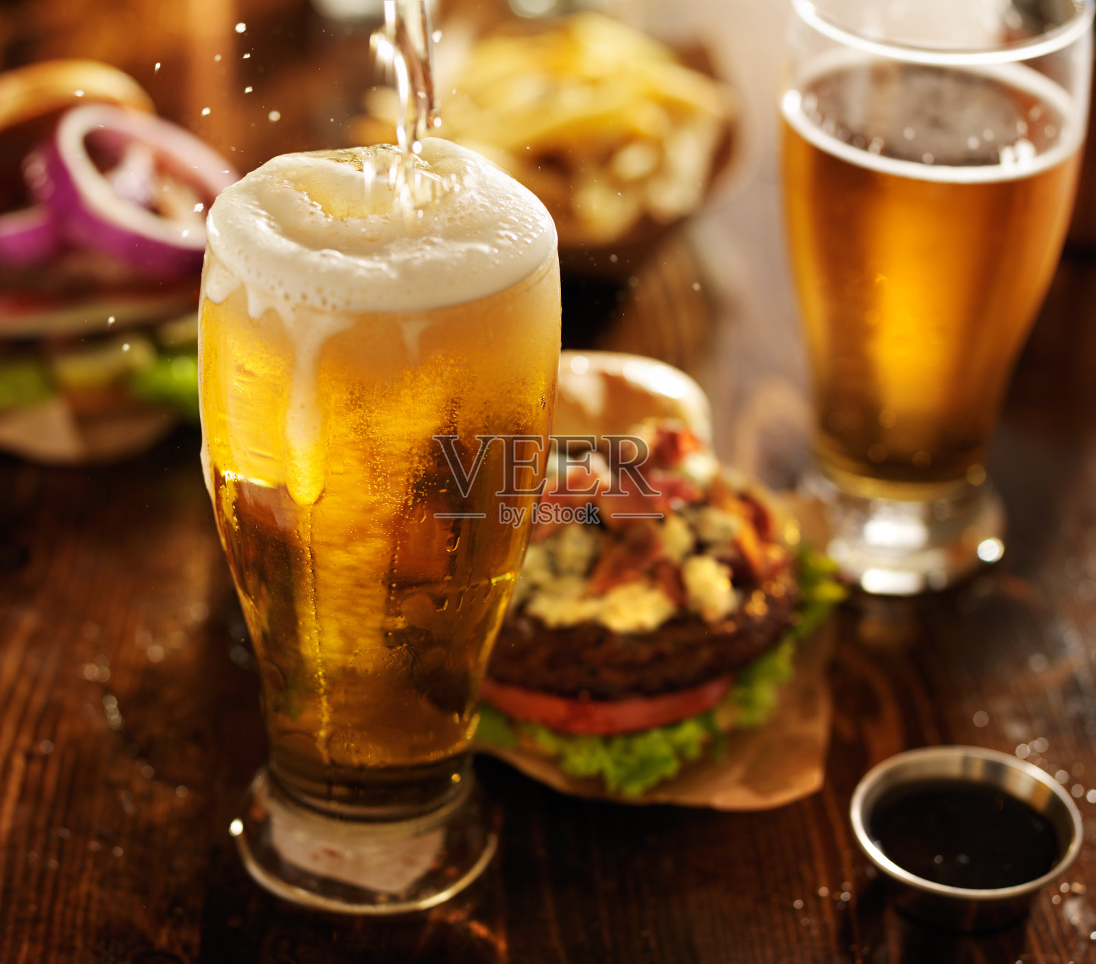 啤酒和美味汉堡一起倒进玻璃杯里照片摄影图片