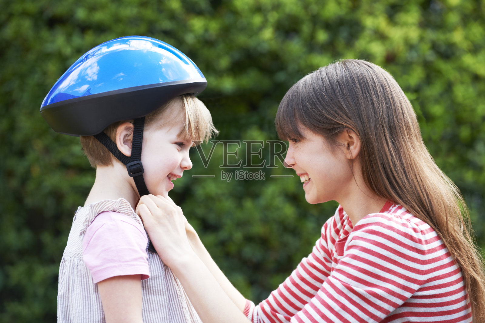 年轻女子给女孩戴上自行车头盔照片摄影图片