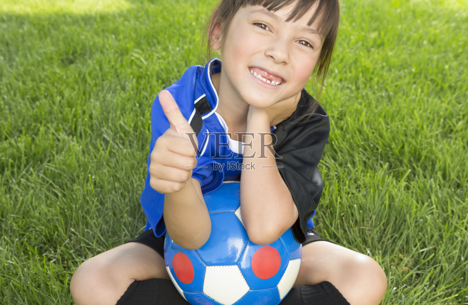小女孩在足球场上竖起大拇指照片摄影图片