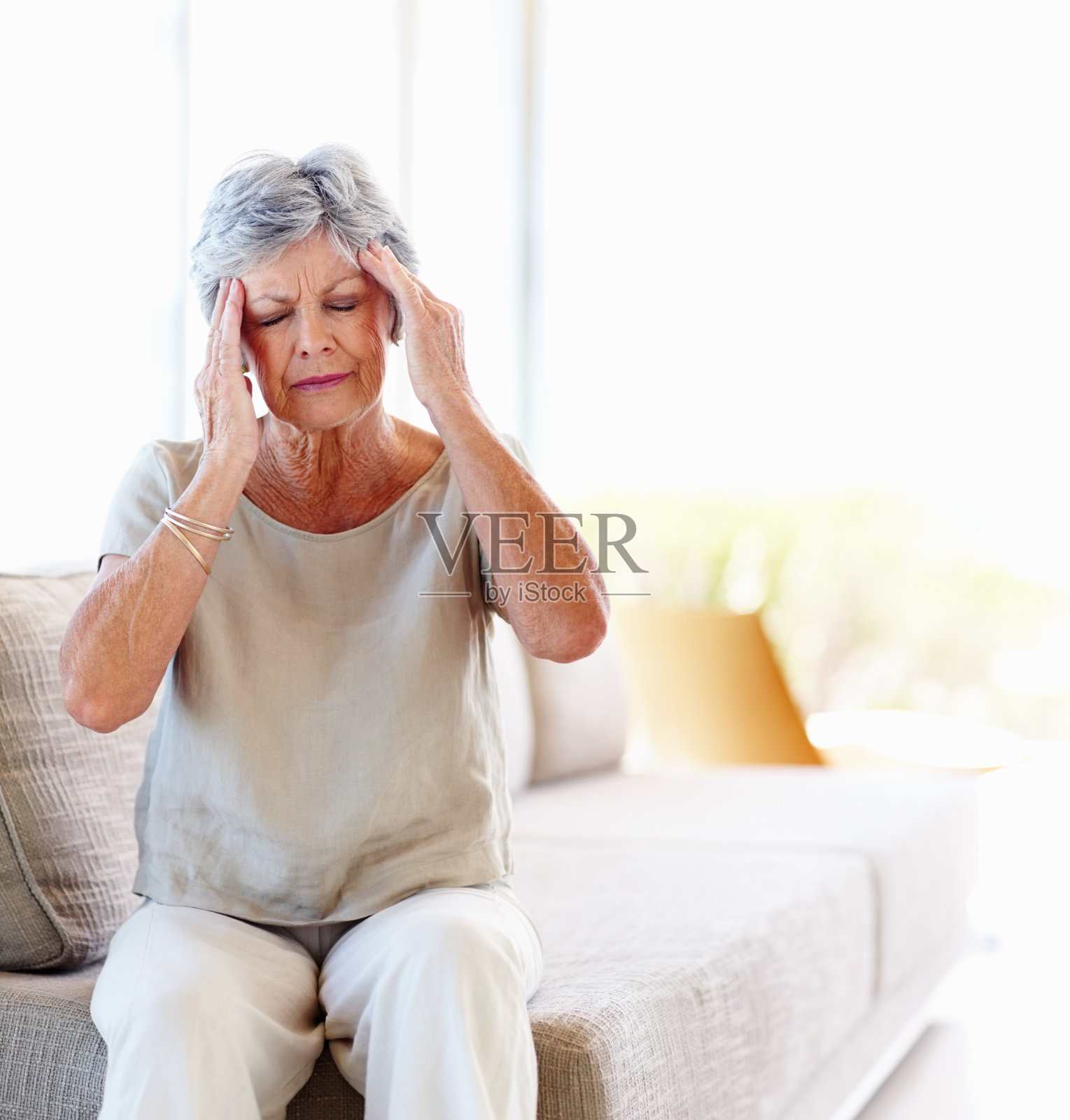 一位年长的妇女抱着她的太阳穴，因为头痛而疼痛照片摄影图片