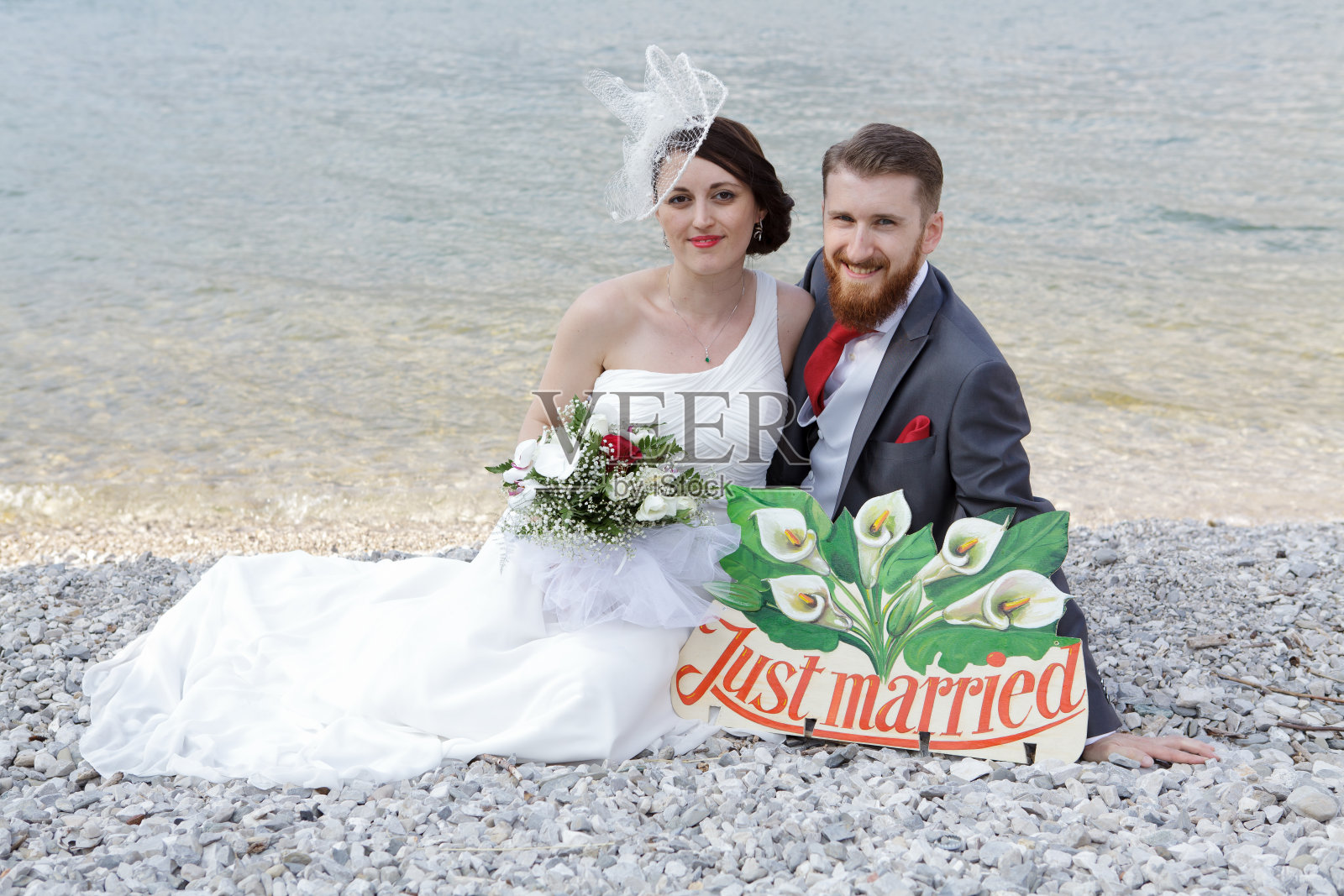 新娘和新郎坐在海滩上照片摄影图片