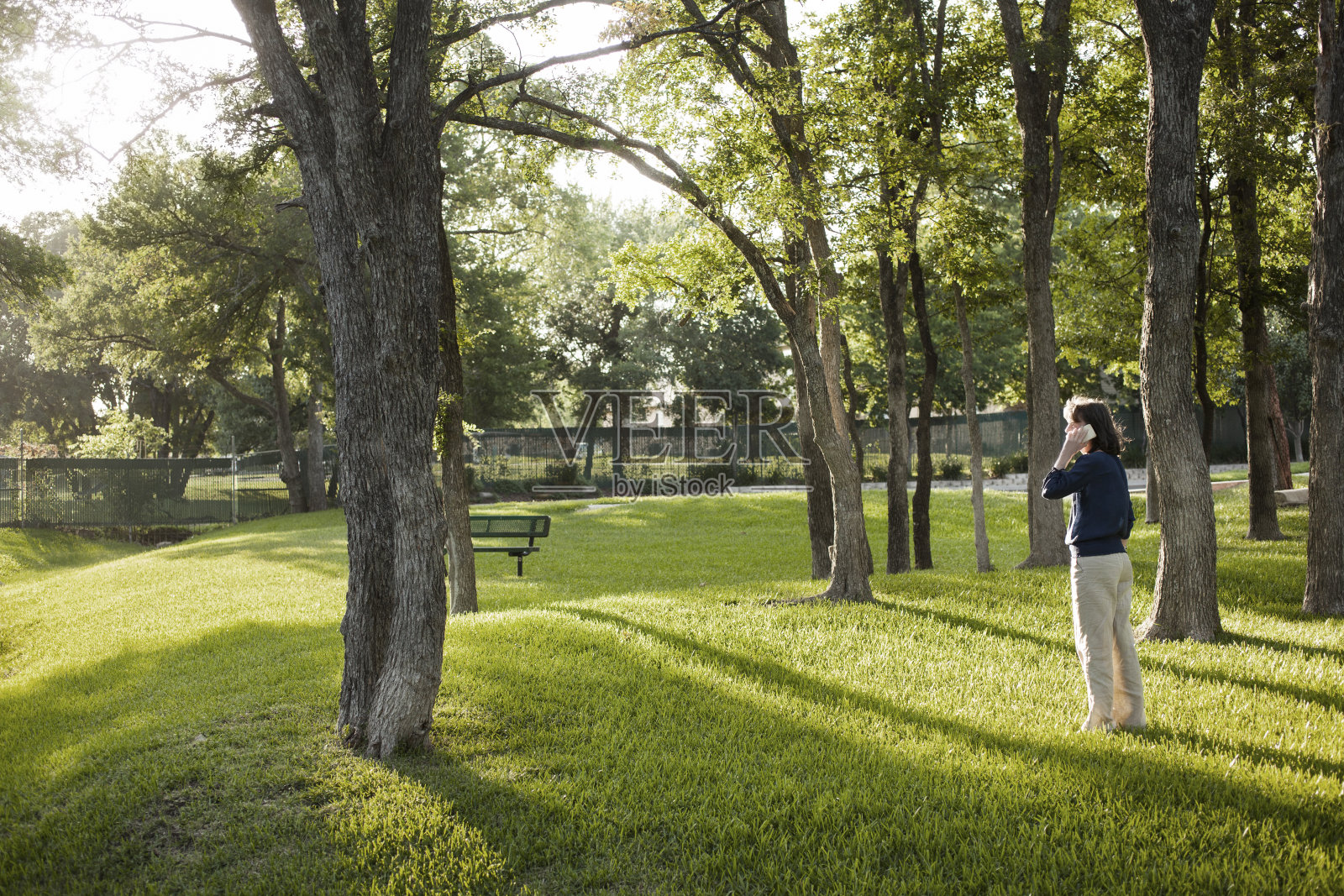 成熟的女人站在公园里打手机。照片摄影图片