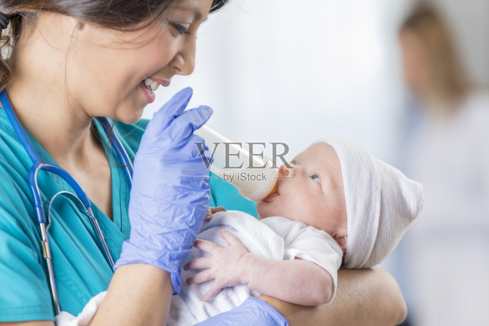 微笑的儿科护士给新生儿喂奶瓶照片摄影图片