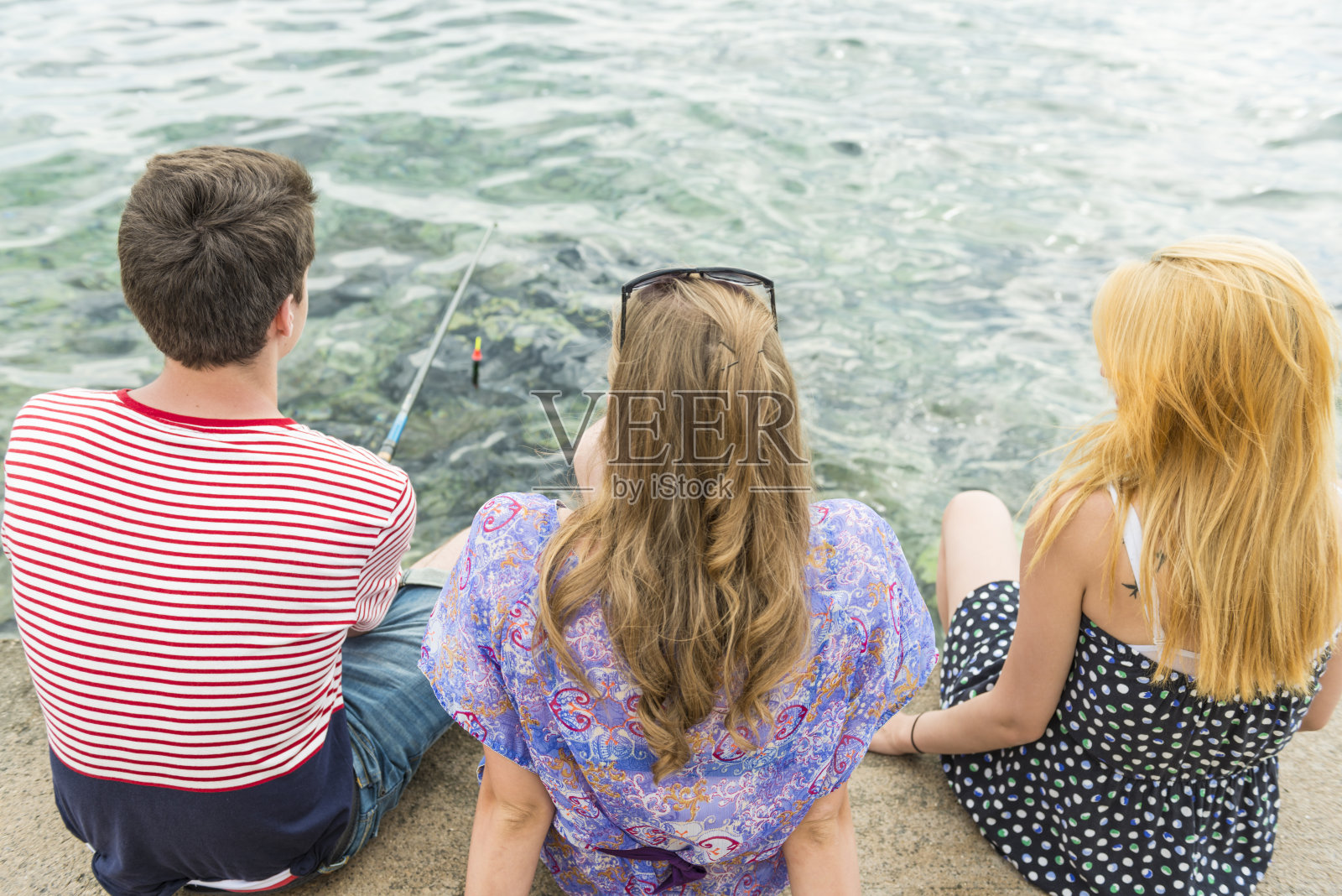 三个年轻人在码头钓鱼照片摄影图片
