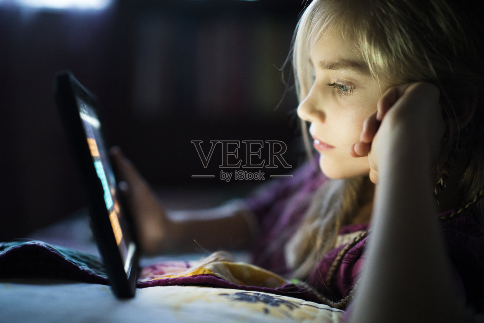 十几岁的女孩晚上在床上用平板电脑看书照片摄影图片