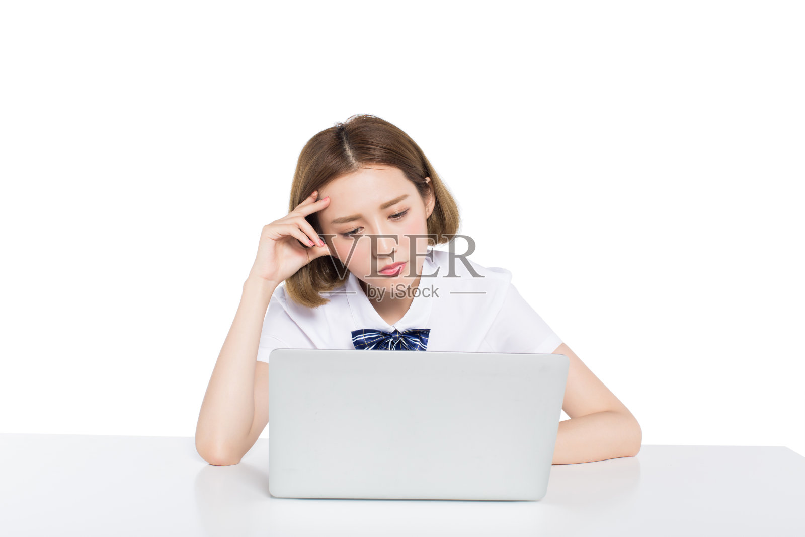 困惑的少女使用笔记本电脑在白色工作室的桌子上照片摄影图片