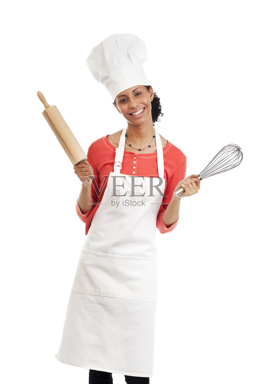 微笑的年轻女厨师与围裙，帽子和厨房用具照片摄影图片