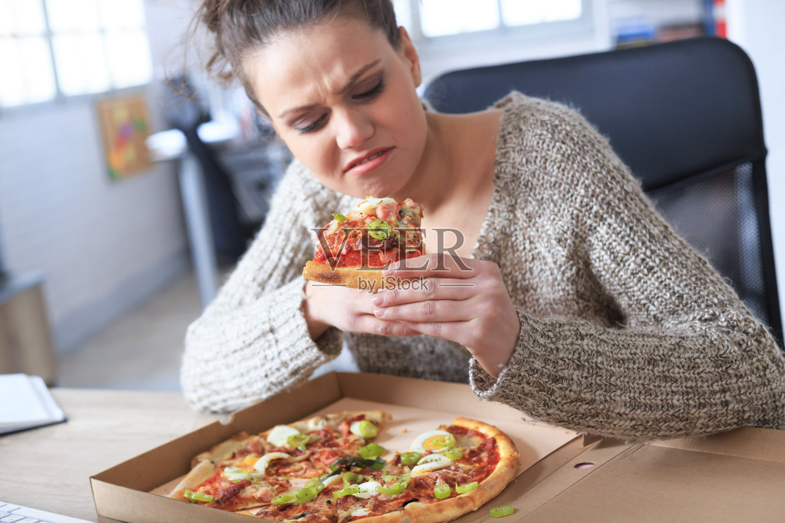 一个讨厌的年轻女人想在办公室吃披萨照片摄影图片