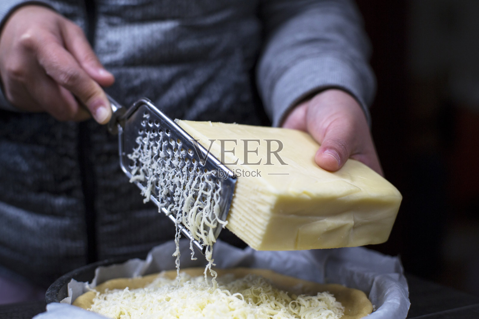 刮着马苏里拉奶酪，覆盖在披萨上照片摄影图片