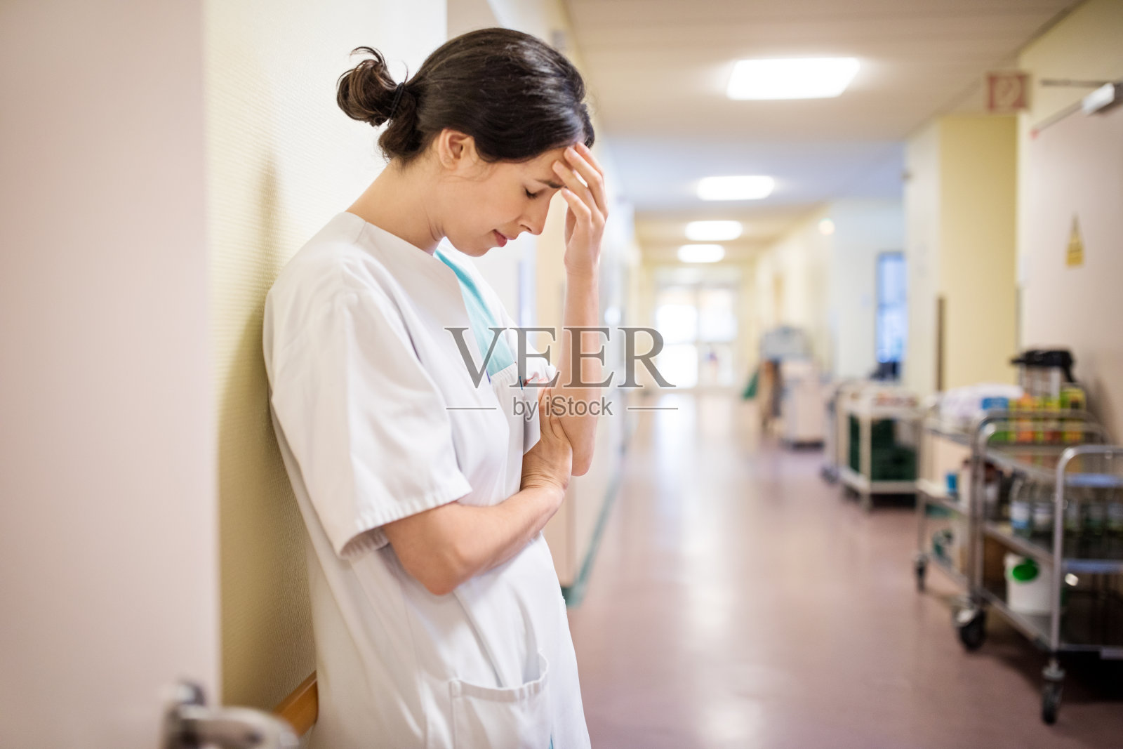 女护士沮丧地站在医院走廊上照片摄影图片