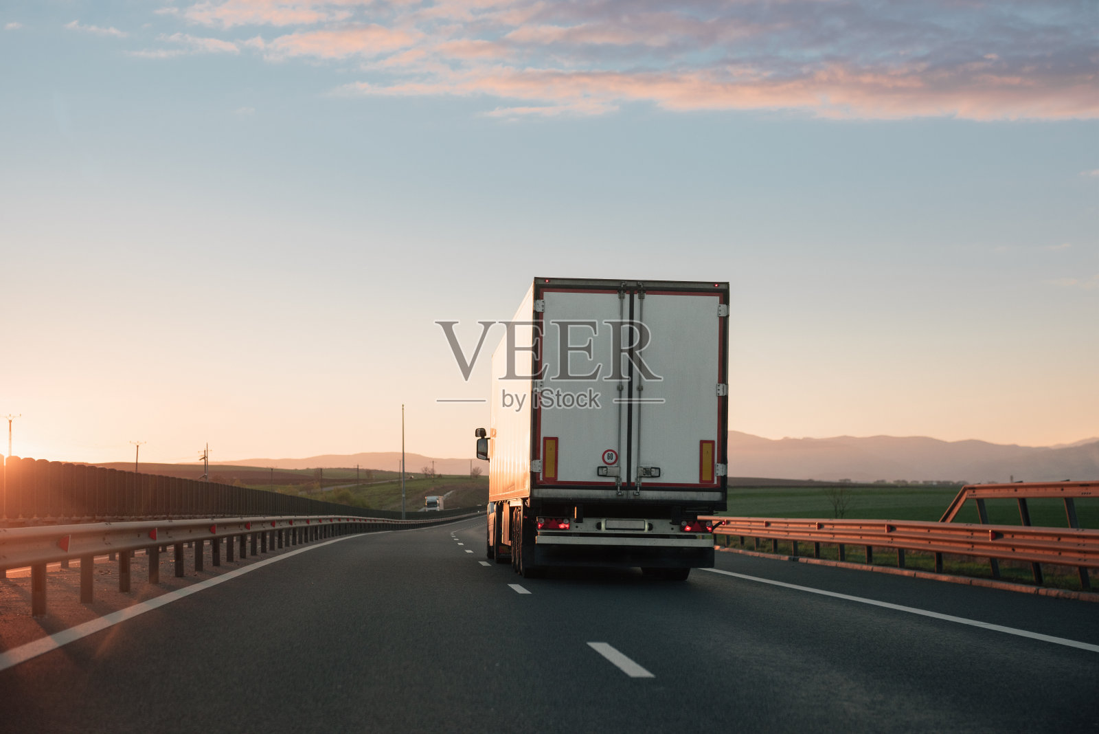 日落时分，一辆白色卡车行驶在两条车道的高速公路上照片摄影图片